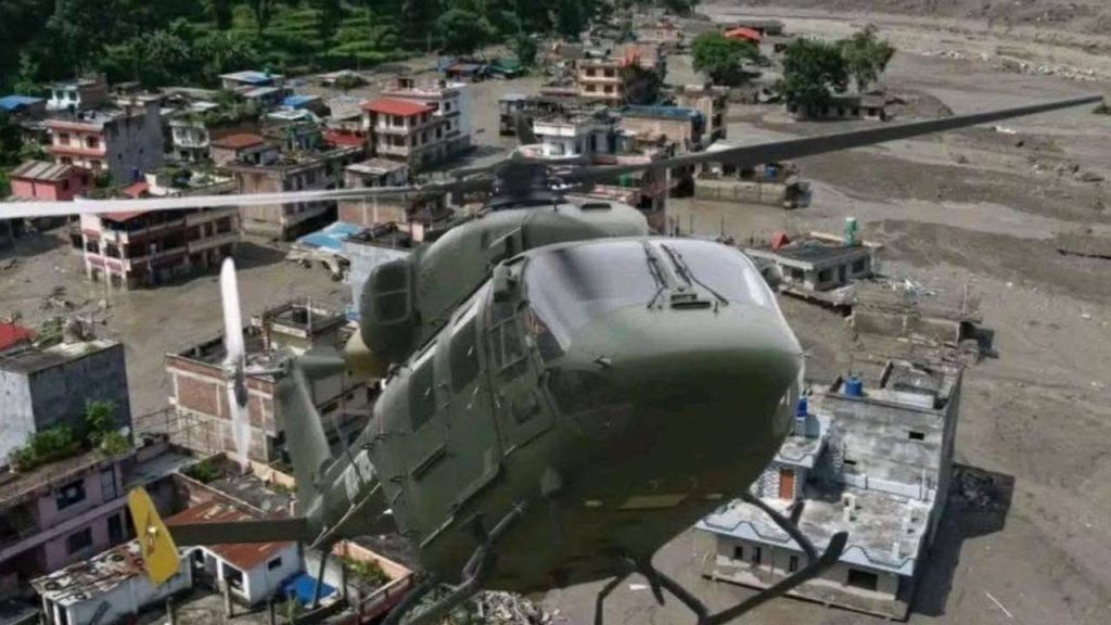 Military rescue helicopter flying over flood-damaged buildings in Rasuwa, Nepal