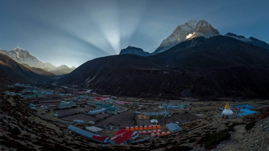 Aerial view of a Khumbu Valley village at sunrise with sun rays over snow-capped Himalayan peaks